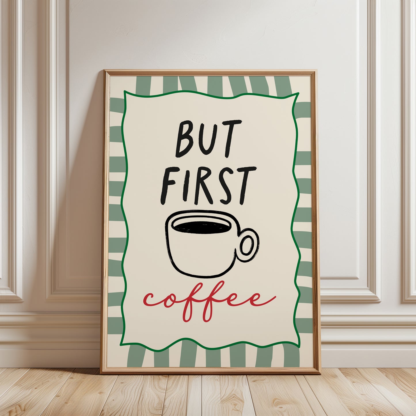 An unframed typographic art print. The print reads “BUT FIRST coffee” with a black coffee cup illustration, a green border, and a cream background.
