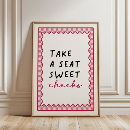 Bright Pink bathroom print with funny quote, take a seat sweet cheeks and a chequered border. Funky wall art